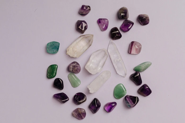 a bunch of different colored stones on a white surface, an album cover, trending on pexels, purple crystal glass inlays, casting a protection spell, they are all laying down, mint