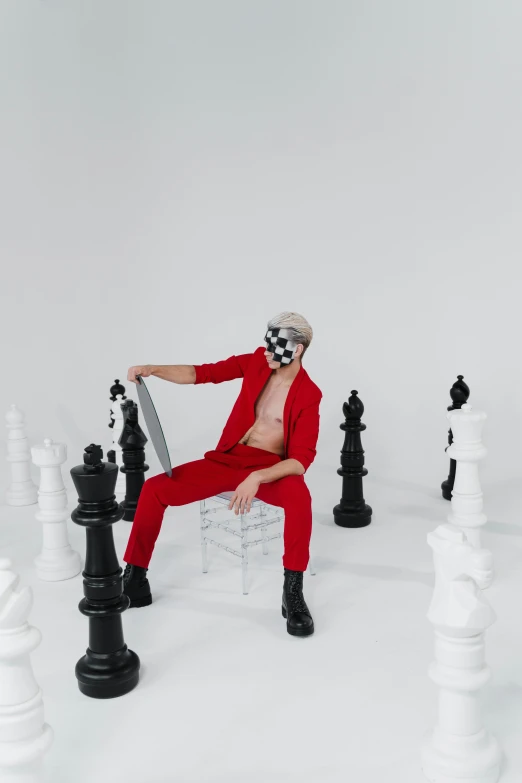 a man sitting on a chair surrounded by chess pieces, an album cover, inspired by Russell Dongjun Lu, trending on pexels, white haired, red body suit, full body photoshoot, gif