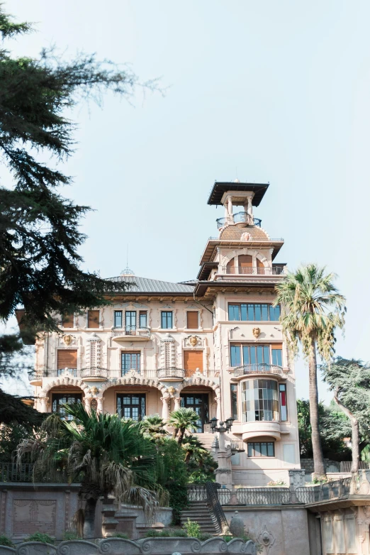 a large building sitting on top of a lush green field, inspired by Vincenzo Cabianca, unsplash, heidelberg school, with palm trees in the back, gold and luxury materials, front elevation view, italy