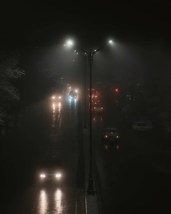 a street filled with lots of traffic at night, an album cover, inspired by Elsa Bleda, realism, moist foggy, lampposts, gray fog, ( ( misty atmosphere ) )