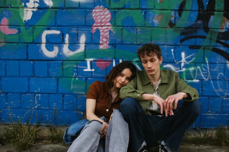 a man and a woman sitting next to each other, an album cover, inspired by Nan Goldin, pexels, renaissance, grimy streets backdrop, teenagers, low colour, juno promotional image