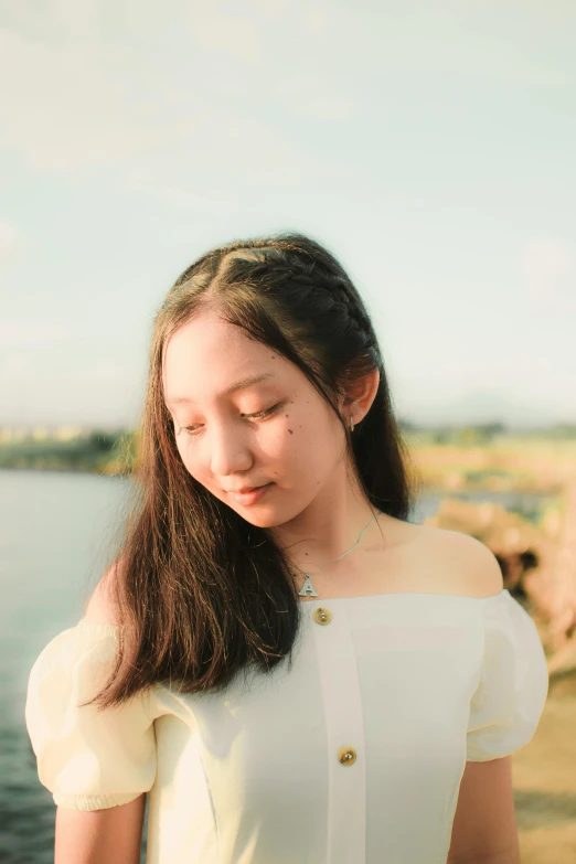 a woman standing next to a body of water, an album cover, inspired by Tang Yifen, pexels contest winner, halfbody headshot, early evening, portrait of white teenage girl, head and shoulders view