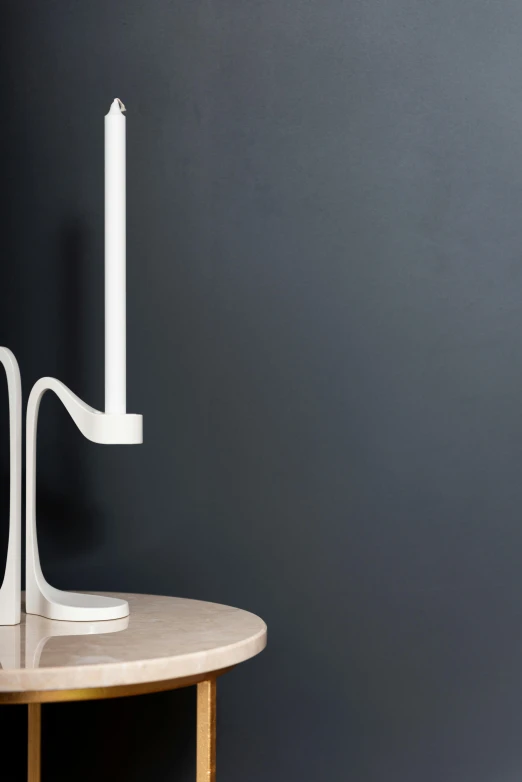 a white candle sitting on top of a wooden table, an abstract sculpture, inspired by George Jamesone, minimalism, loop lighting, with pipes attached to it, eero aarnio, low detail