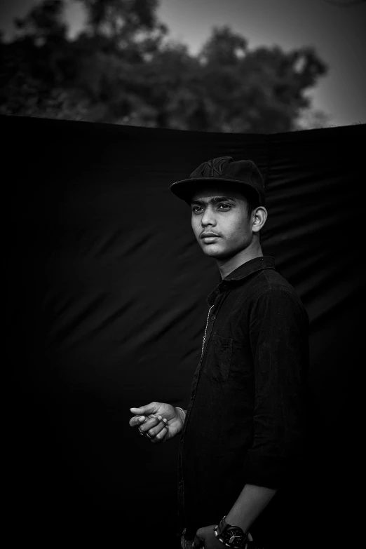 a black and white photo of a man in a hat, a black and white photo, by Basuki Abdullah, black teenage boy, ((portrait)), wearing black modern clothes, low iso