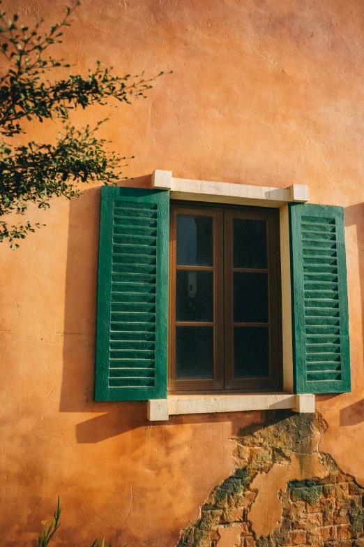 a couple of windows sitting on the side of a building, inspired by Michelangelo Buonarotti, unsplash contest winner, traditional corsican, green and orange theme, ancient mediterranean village, sunfaded