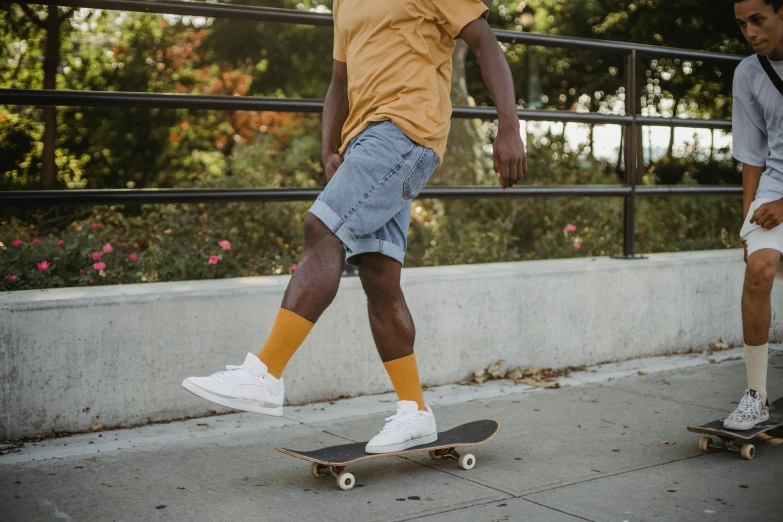 a man riding a skateboard down a sidewalk, pexels contest winner, gray shorts and black socks, white and yellow scheme, wearing wheat yellow gauze, denim
