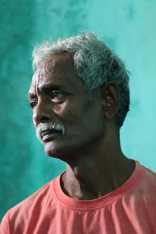 a man standing in front of a green wall, by Sunil Das, the look of an elderly person, grey mustache, lightly dirty face, fisherman