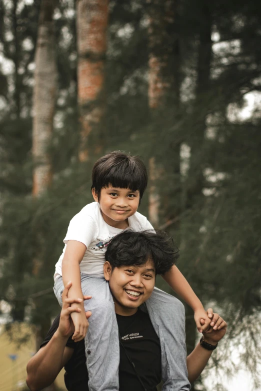 a man carrying a little boy on his shoulders, a picture, by Basuki Abdullah, pexels contest winner, headshot profile picture, square, happy friend, with trees