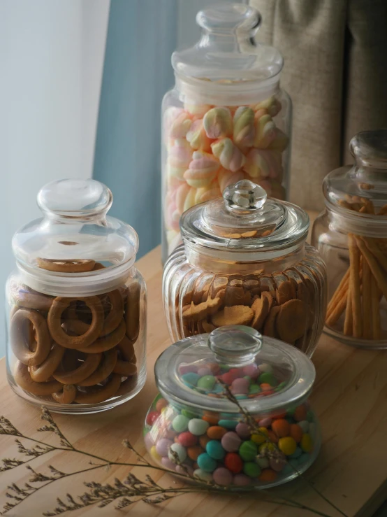 a wooden cutting board topped with jars filled with candy and pretzels, a still life, by Charlotte Harding, pexels, glass labware, jakarta, indoor, instagram story