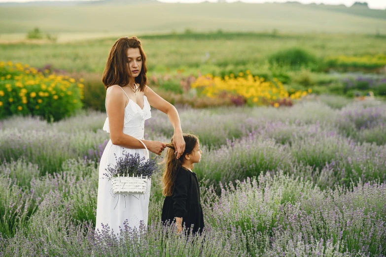 a woman standing next to a little girl in a field, by Emma Andijewska, pexels contest winner, skincare, lavender flowers, woman with braided brown hair, various posed