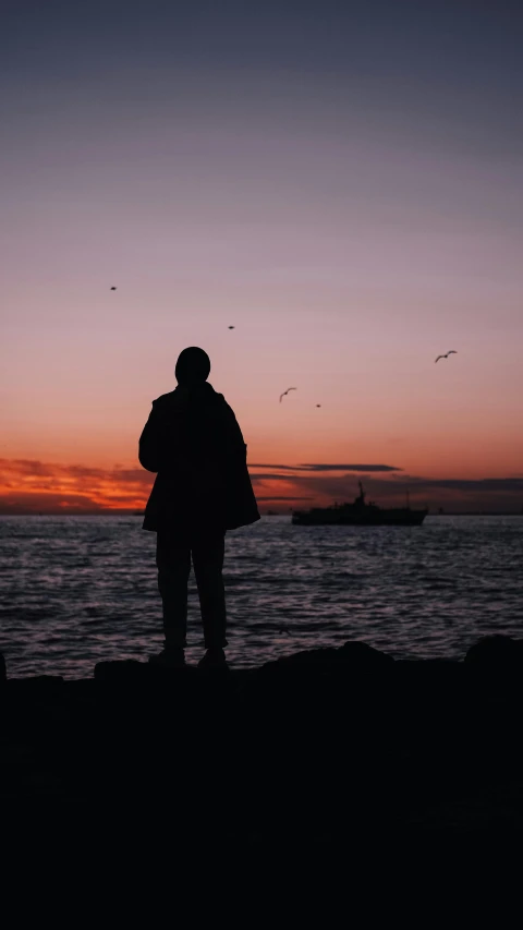 a man standing on top of a rock next to the ocean, pexels, romanticism, outlined silhouettes, backlit shot girl in parka, instagram photo, harbor