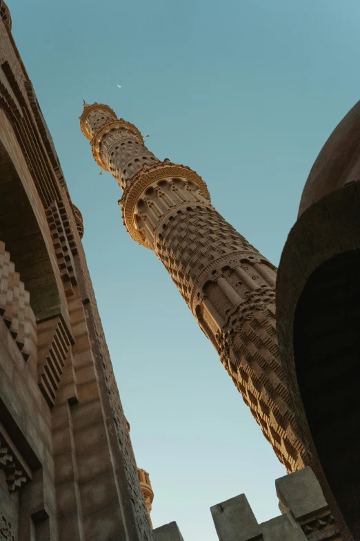 a tall tower sitting in the middle of a city, arabesque, in egypt, spiralling, looking up at camera, brown