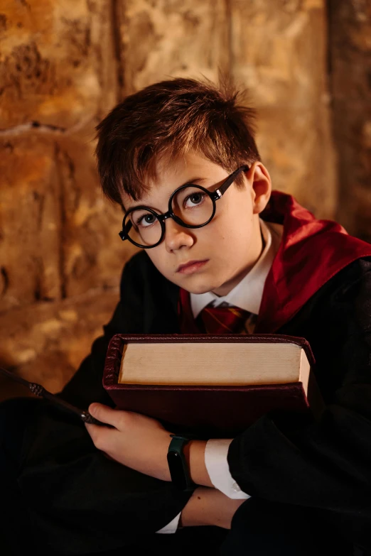 a young boy dressed as harry potter holding a book, a portrait, inspired by Fuller Potter, pexels, in a medieval crypt, spectacles, ( ( theatrical ) ), resin