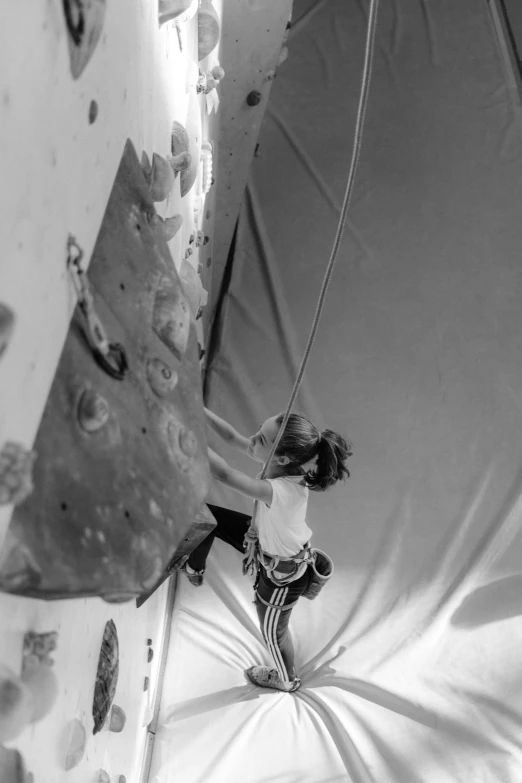 a black and white photo of a person on a climbing wall, by Dave Melvin, silks, female ascending, kano), round about to start