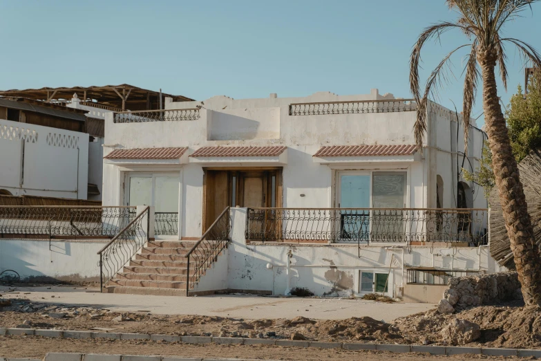 a white house with a palm tree in front of it, a digital rendering, pexels contest winner, the dead sea, ruined subdivision houses, background image, terraces