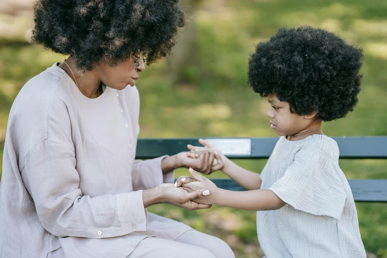 a woman and a child sitting on a bench, pexels, symbolism, white bandage tape on fists, with afro, reaching out to each other, game and watch