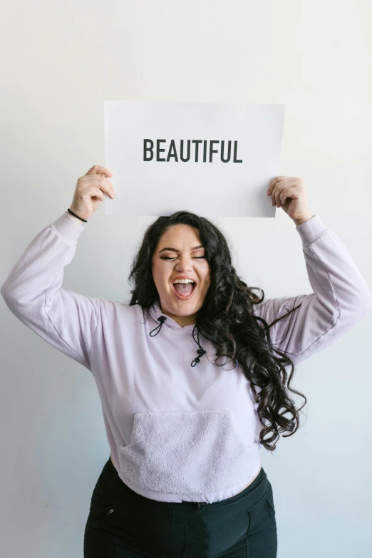 a woman holding a sign that says beautiful, pexels contest winner, aestheticism, plus size woman, joyful look, female with long black hair, julia hetta