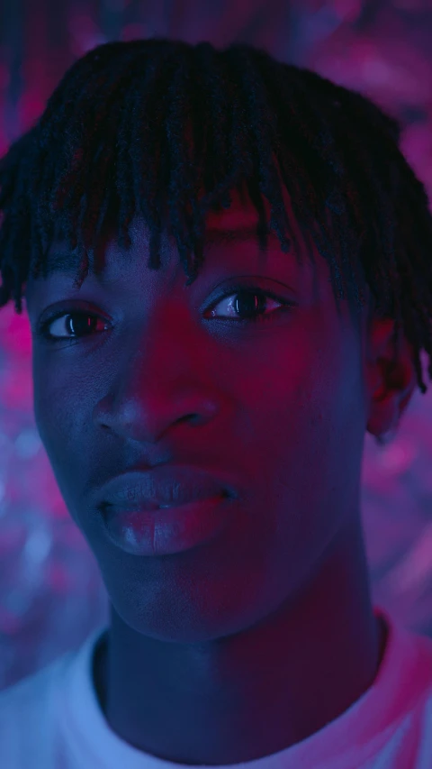 a close up of a person wearing a white shirt, an album cover, inspired by Xanthus Russell Smith, trending on pexels, glowing magenta face, high blue lights, black teenage boy, still frame from a movie