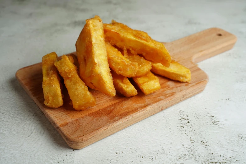 a wooden cutting board topped with french fries, a picture, jakarta, 6 pack, mango, battered