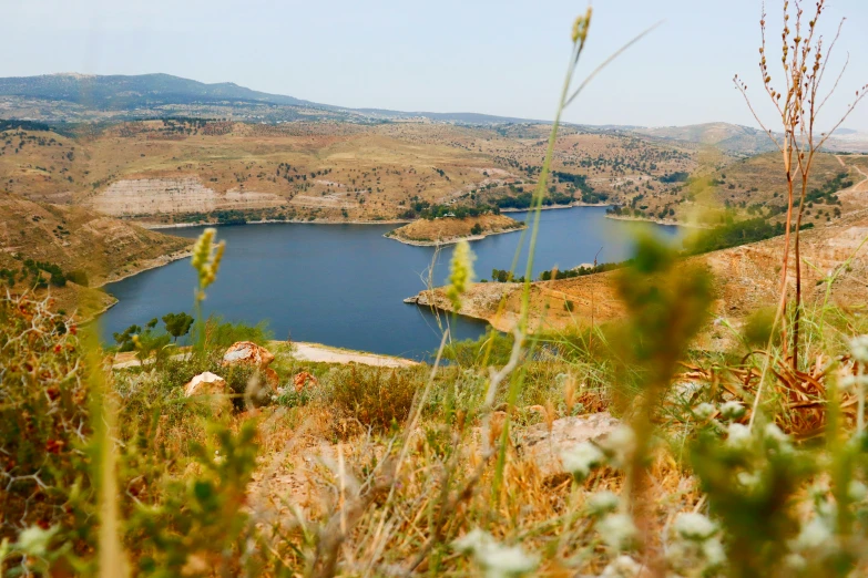 a large body of water sitting on top of a lush green hillside, a portrait, drumheller, mountains and lakes, exterior shot, conde nast traveler photo