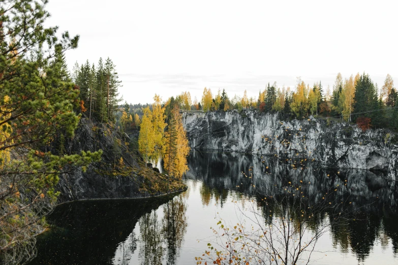 a large body of water surrounded by trees, by Jaakko Mattila, pexels contest winner, hurufiyya, rock quarry location, thumbnail, autum, 1 2 9 7