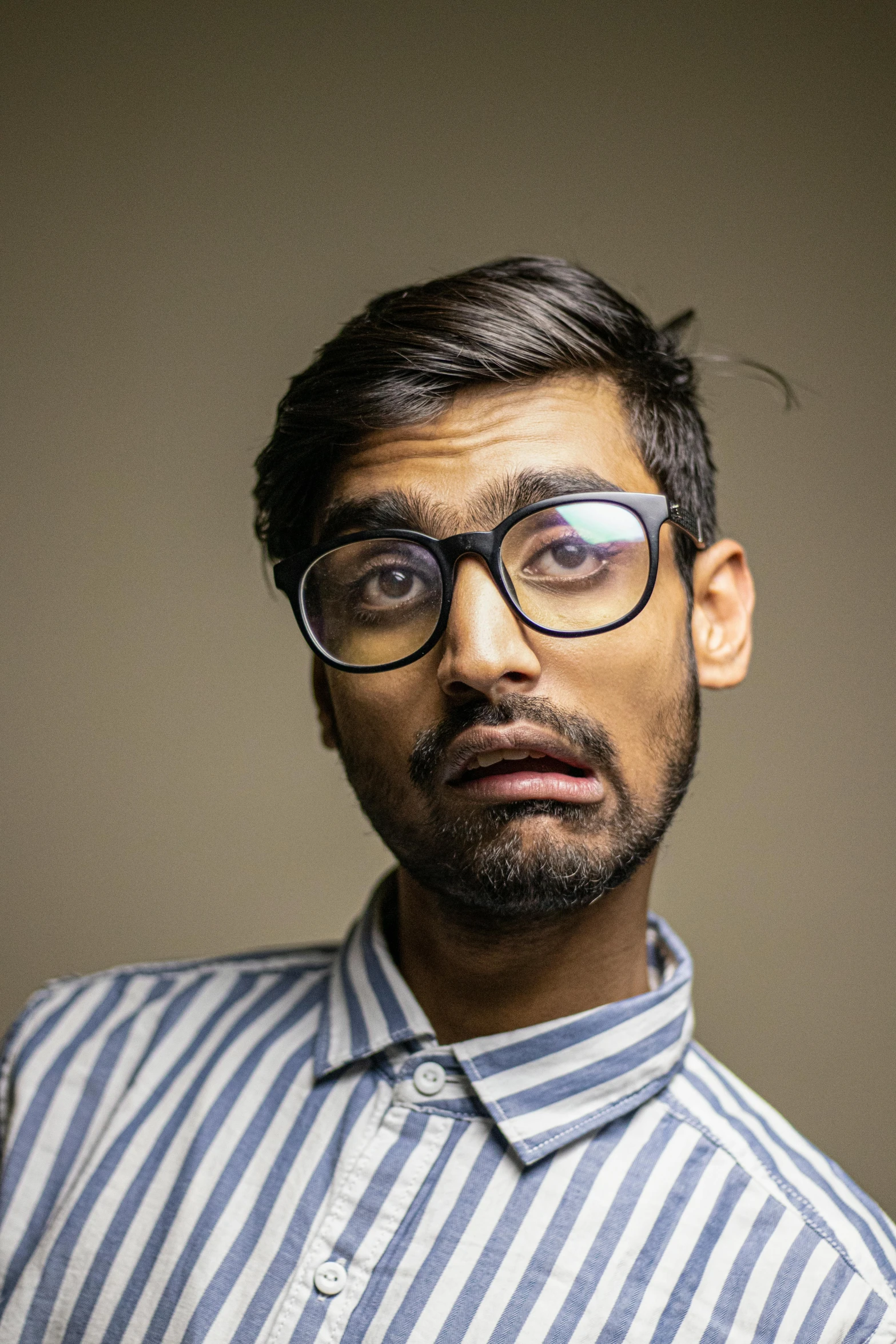 a man with a surprised look on his face, shutterstock, hyperrealism, a portrait of rahul kohli, square rimmed glasses, taken in the late 2010s, androgynous male