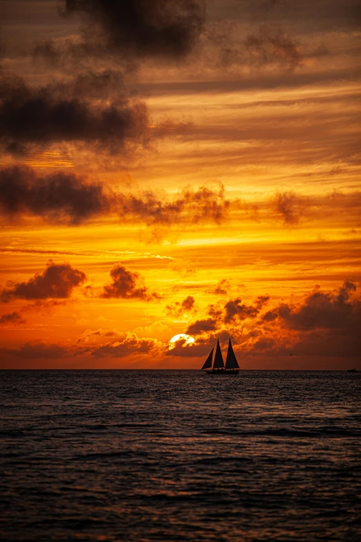 two sailboats in the ocean at sunset, by Niklaus Manuel, pexels contest winner, aruba, orange clouds, silhouette, vacation photo