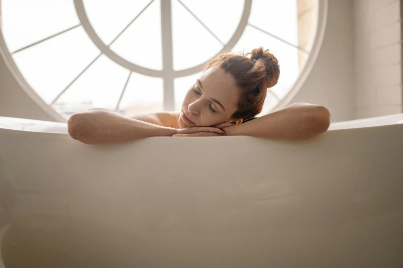 a woman that is laying down in a bathtub, pexels, renaissance, leaning against the window, profile image, with a round face, afternoon time