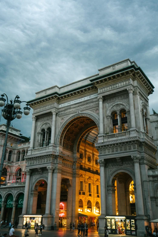 a group of people that are standing in front of a building, by Carlo Martini, pexels contest winner, neoclassicism, giant majestic archways, evening lights, promo image, square