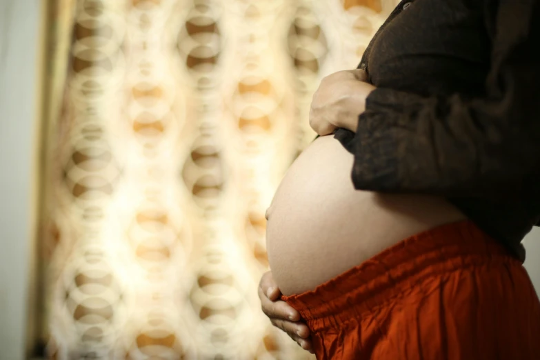 a pregnant woman standing in front of a curtain, intricate foreground, warm coloured, resin, no cropping
