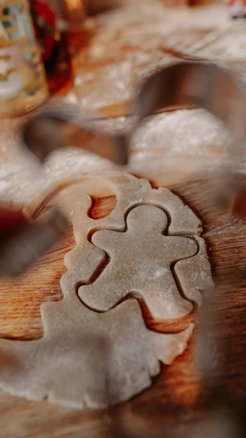 a cookie cutter sitting on top of a wooden cutting board, inspired by Rudolph F. Ingerle, trending on pexels, renaissance, blurred detail, 15081959 21121991 01012000 4k, spiralling, made of clay