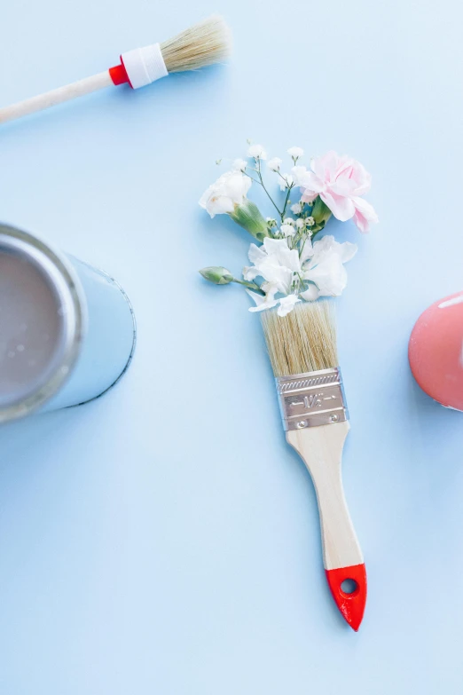 a paint brush sitting next to a can of paint, trending on unsplash, blue flowers accents, romantic lead, pink and blue, carefully crafted