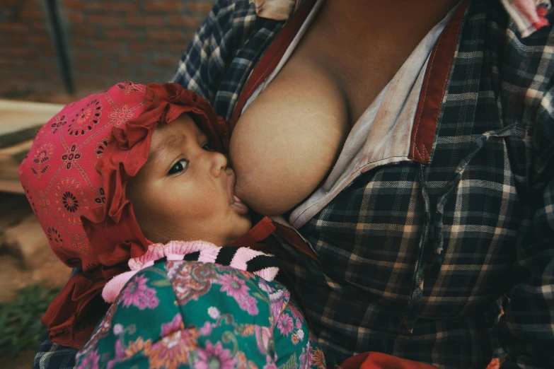 a close up of a person holding a baby, by Elsa Bleda, pexels contest winner, renaissance, with a large breasts, bolivian cholitas, asian girl, bralette