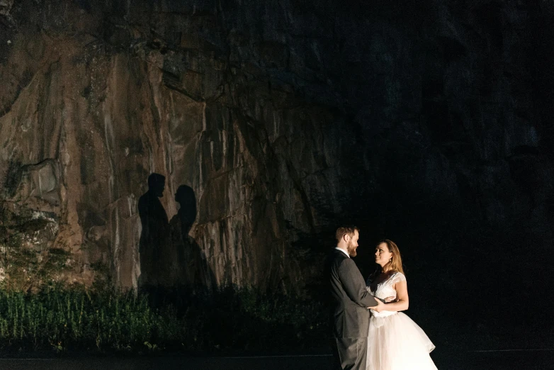 a bride and groom standing in front of a waterfall, unsplash, cave lighting, evening sunlight, thumbnail, portait image