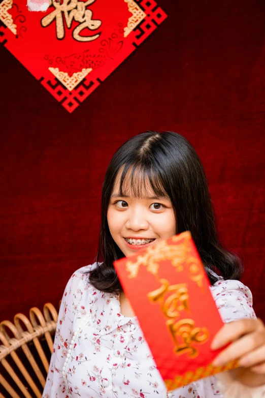 a woman holding a red packet in front of a red wall, avatar image