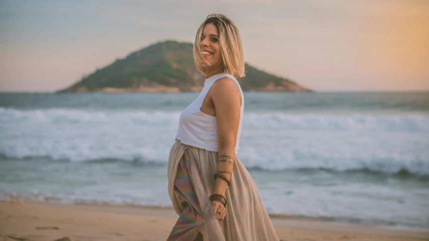 a woman standing on top of a beach next to the ocean, maternity feeling, avatar image, são paulo, smiling