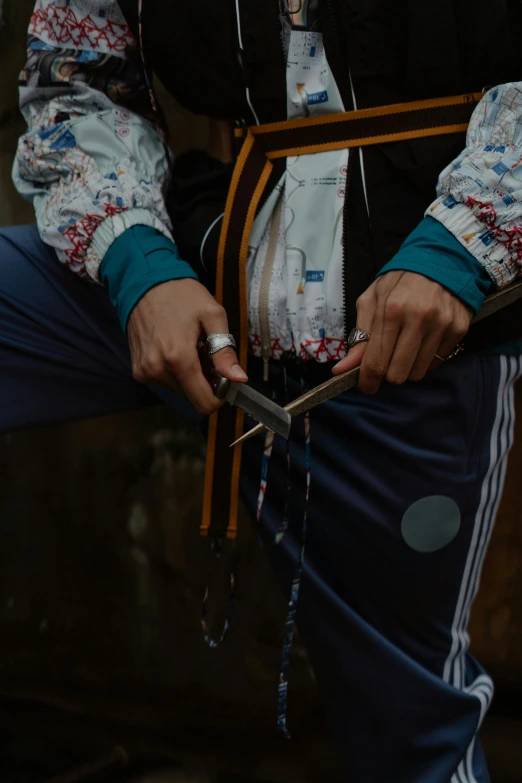 a man holding a pair of scissors in his hands, an album cover, by Attila Meszlenyi, trending on unsplash, traditional clothing, belaying, drip, wearing adventure gear