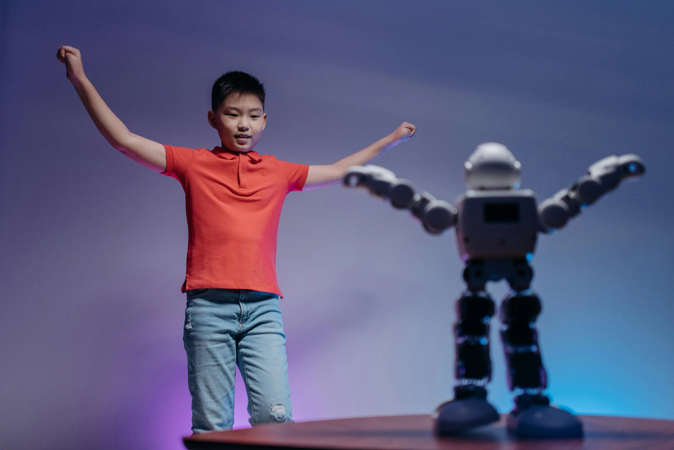 a young boy standing on top of a table next to a robot, pexels contest winner, interactive art, dancing, avatar image, performance, peter chan