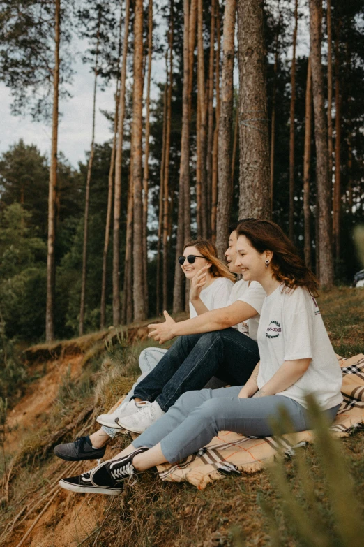 two women sitting on a blanket in the woods, pexels contest winner, happening, jeans and t shirt, beautiful swedish forest view, waving, dressed in a white t shirt