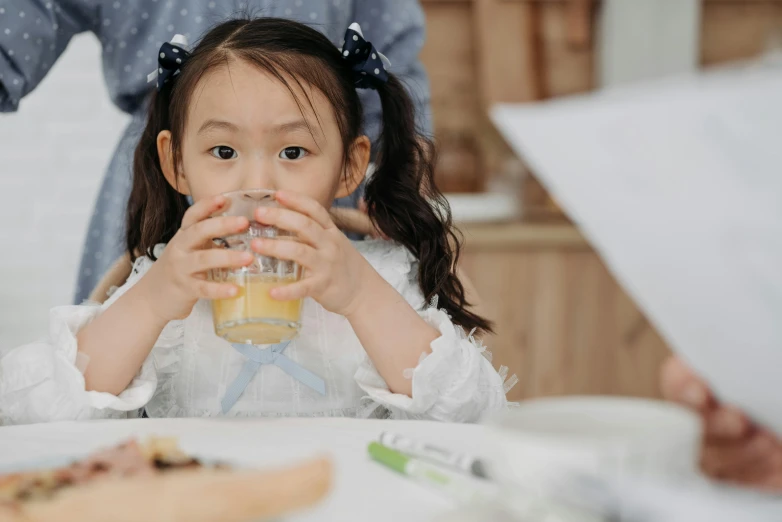 a little girl sitting at a table drinking from a glass, pexels contest winner, manuka, student, diy, katherine lam