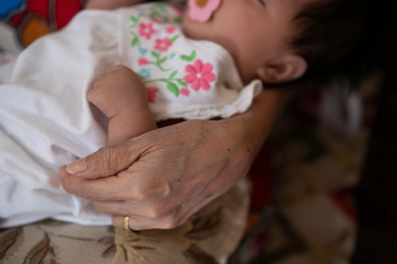 a close up of a person holding a baby, nivanh chanthara, an elderly, partially cupping her hands, resting