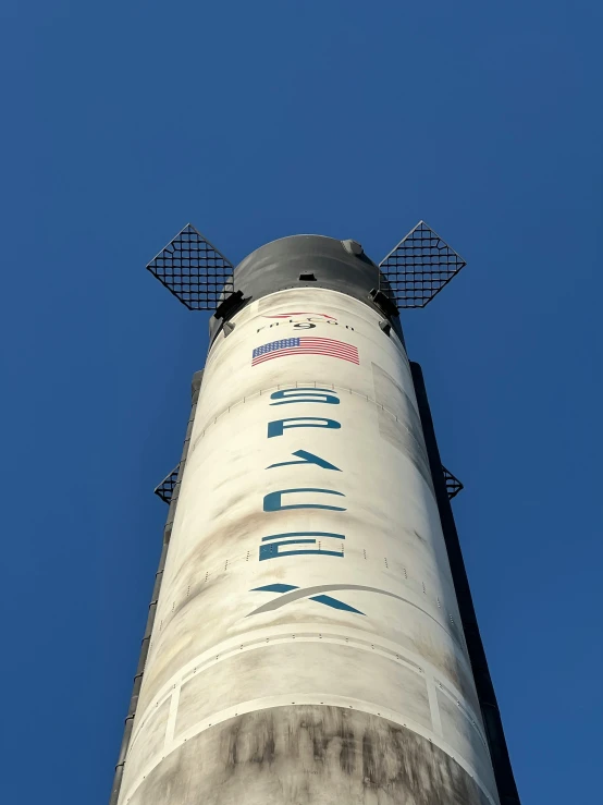 a tall pole with a blue sky in the background, an album cover, by Jason Felix, unsplash, spacex, chimney, museum photo, back - view