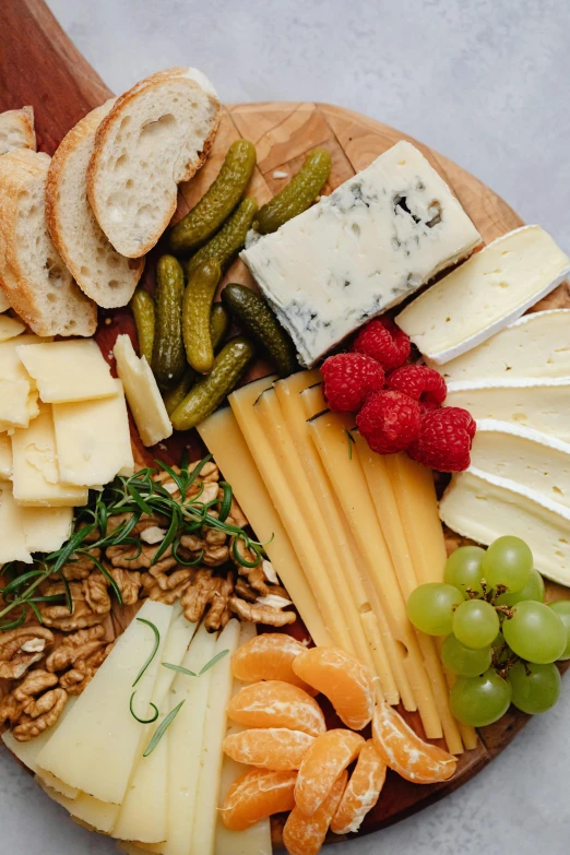 a wooden board topped with lots of different types of cheese, detailed product image