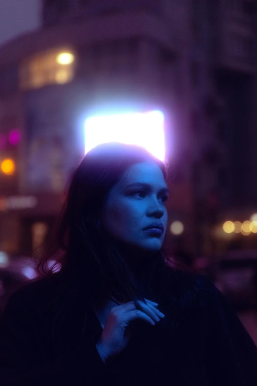 a woman standing on a city street at night, an album cover, pexels contest winner, blue lights and purple lights, julia hetta, film still promotional image, people