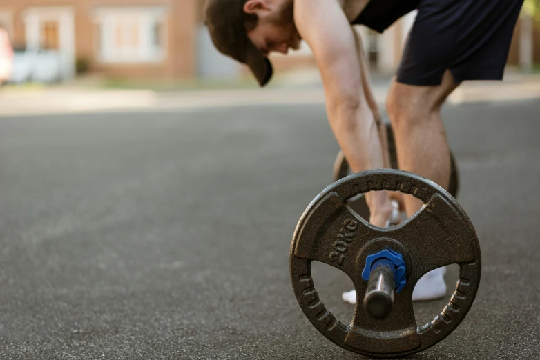 a man bending over with a barbell in his hand, pexels contest winner, wheels, background image, lachlan bailey, spring season