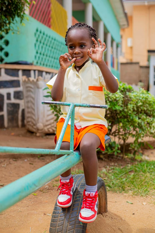 a little girl that is sitting on a swing, very kenyan, waving and smiling, young male with walking stick, school courtyard