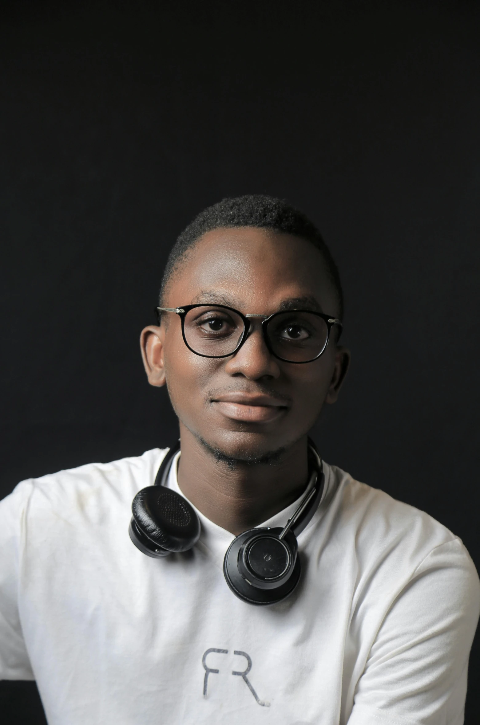 a man wearing headphones and a white shirt, by Chinwe Chukwuogo-Roy, pexels contest winner, hurufiyya, in front of white back drop, spectacled, panel of black, around 1 9 years old