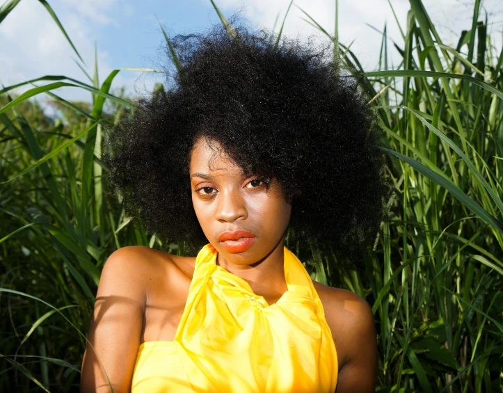 a woman in a yellow dress standing in tall grass, an album cover, by Lily Delissa Joseph, pexels contest winner, natural hair, headshot photo, vibrant.-h 704, woman with black hair