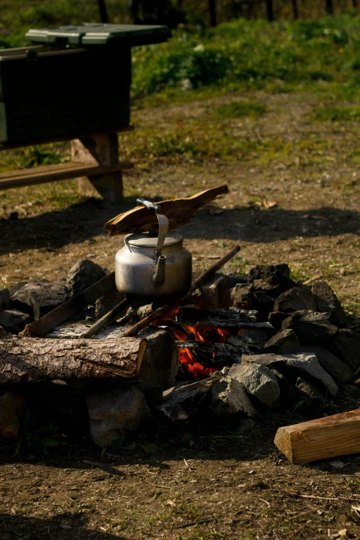 a kettle sitting on top of a fire in a field, with a wooden stuff, slide show, frontal shot, explore