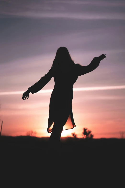 a woman standing on top of a grass covered field, ((sunset)), woman in black robes, trending photo, shrugging